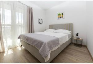 a white bedroom with a large bed and a window at Apartments Vulić in Omiš