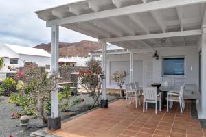 un patio con pérgola blanca, mesa y sillas en La Casita, en Playa Blanca