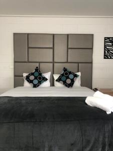 a bedroom with a large bed with black and white pillows at Gladstone CBD Motel in Gladstone