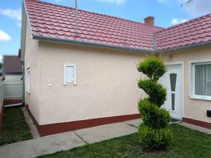 a house with a red roof and a bush at Margó Vendégházak 2 in Hajdúszoboszló