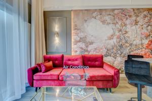 un sofá rojo en una habitación con una pared floral en Allure NOVA Aparthotel, en Szczecin