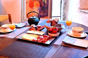 a wooden table with food and glasses of orange juice at Mas d'Aval in Le Vigan +10 photos