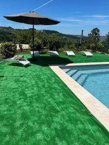a swimming pool with an umbrella next to a swimming pool at Quinta da Travessa in Cinfães