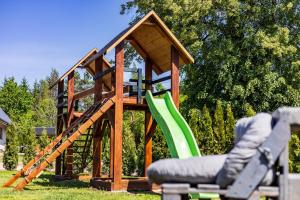 a wooden play house with a green slide at SZUMI LAS in Białowieża