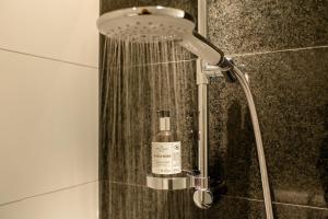 um chuveiro na casa de banho com uma garrafa de sabão em Motel One München - Deutsches Museum em Munique