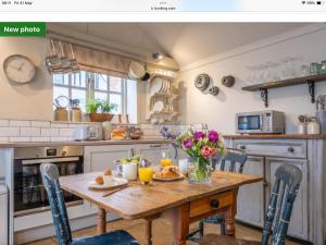 a kitchen with a wooden table with flowers on it at The Old Candle Shop in Little Walsingham +16 photos
