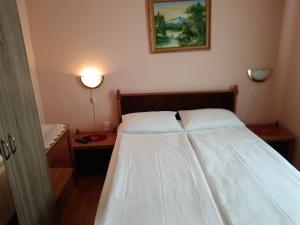 ハイドゥソボスローにあるMargó Vendégházak 2のベッドルーム1室(ベッド1台、ランプ付きテーブル付)
