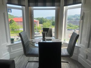 a dining room with a table and chairs and windows at Teviot View Holiday Let’s Hawick in Hawick