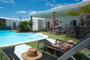 un patio avec une table et des chaises à côté d'une piscine dans l'établissement Finca del Moral, à Tinajo