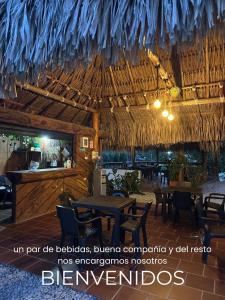 a restaurant with a straw roof and tables and chairs at finca campestre las heliconias in Puerto Triunfo