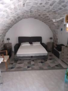 a bedroom with a bed in a stone wall at Studio idéal pour vos vacances in Saint Alban Auriolles