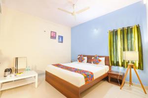 FabHotel Namaha Suites في حيدر أباد: غرفة نوم بسرير وطاولة مع مصباح