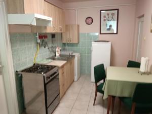 a kitchen with a stove and a sink and a table at Margó Vendégházak 2 in Hajdúszoboszló