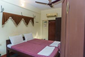 a bedroom with a bed with a red and white blanket at Kailash Guest House in Puducherry