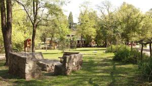 a park with a bench and trees and a house at Hostel El Rincon in Villa General Belgrano