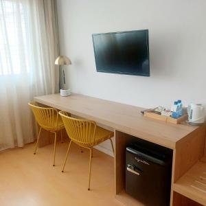 escritorio con 2 sillas y TV en la pared en Daniya Alicante, en Alicante