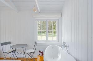 ein Bad mit einer Badewanne, einem Tisch und Stühlen in der Unterkunft Coastal Cabin Engure in Engure