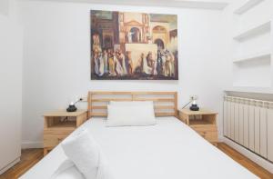 - une chambre avec un lit blanc et une peinture murale dans l'établissement TuApartamento centro Estafeta Deluxe, à Pampelune