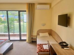 a room with a bed and a desk and a tv at Maria Garden in Kranevo
