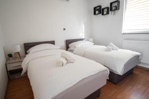three beds in a room with white sheets and pillows at Natura Apartmani in Ljubuški +37 photos