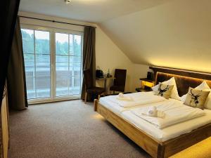 a bedroom with a large bed and a large window at Hotel Reich am Ebnisee in Kaisersbach