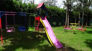 a playground with a slide in the grass at Wooden Knee Cottages Nanyuki in Nanyuki