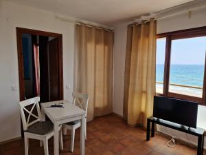 a living room with a table and chairs and a view of the ocean at Apartamentos Wundermar in Torredembarra