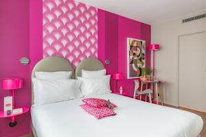 a pink bedroom with a white bed and pink walls at Appart'City Collection Paris Vélizy in Vélizy-Villacoublay