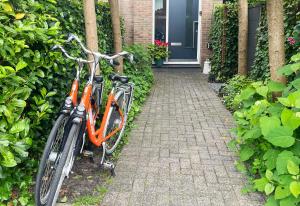 an orange bike parked in front of a house at The West Wing Bloemendaal in Bloemendaal