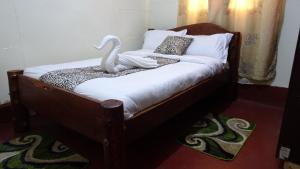 a bedroom with a bed with a swan statue on it at Wooden Knee Cottages Nanyuki in Nanyuki