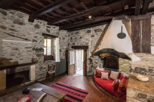 a living room with a red couch in a stone building at Μilia Mountain retreat in Vlátos