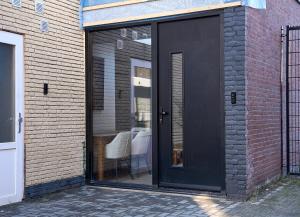 eine schwarze Tür in einem Backsteingebäude mit einem Tisch in der Unterkunft The Vault - Eindhoven - by T&S in Eindhoven