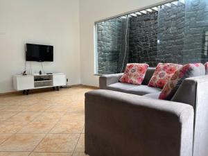 a living room with two couches and a tv at Casa agradável com piscina, ar condicionado e churrasqueira in Natal
