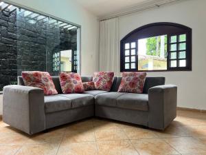 a living room with a couch with red pillows at Casa agradável com piscina, ar condicionado e churrasqueira in Natal