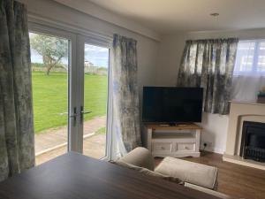 a living room with a tv and a sliding glass door at Chateau Seaside in Withernsea