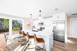 a kitchen with white cabinets and a kitchen island with chairs at The Bay House-Bayfront serenity, stunning sunsets in Ward Ridge