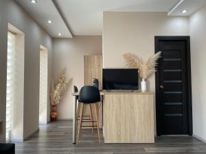a room with a desk with a television and a stool at Sky Apartman in Nyíregyháza