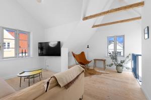 a white living room with a couch and a tv at Lovely Holiday Home In The Heart Of Løkken in Løkken