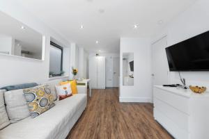 a living room with a white couch and a flat screen tv at Manor House Studios By Morethanstays in London