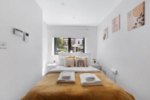 a white bedroom with a bed with two towels on it at Manor House Studios By Morethanstays in London
