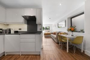 a kitchen and living room with a table and chairs at Manor House Studios By Morethanstays in London