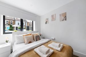 a white bedroom with a large bed with two pillows at Manor House Studios By Morethanstays in London