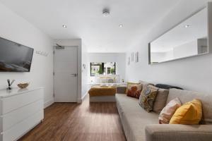 a white living room with a couch and a bedroom at Manor House Studios By Morethanstays in London