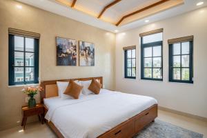 a bedroom with a large white bed with windows at AnnA Villa - Novaworld Phan Thiết in Bình Tú +45 photos
