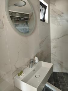 La salle de bains blanche est pourvue d'un lavabo et d'un miroir. dans l'établissement Marina Sarafovo, à Bourgas