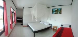a white room with a bed and a red rug at Volcano 3 hotel in Kintamani