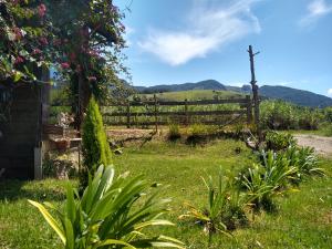 un jardín con valla y un campo con montañas en Quarto Pérola simples, en Gonçalves 40 fotos más