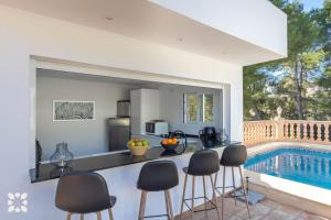 a kitchen with a counter and chairs next to a swimming pool at Villa La Morena by Abahana Villas in Fanadix