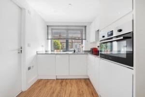 a white kitchen with white cabinets and a window at Manor House Studios By Morethanstays in London