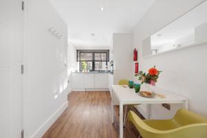 a white room with a table and yellow chairs at Manor House Studios By Morethanstays in London